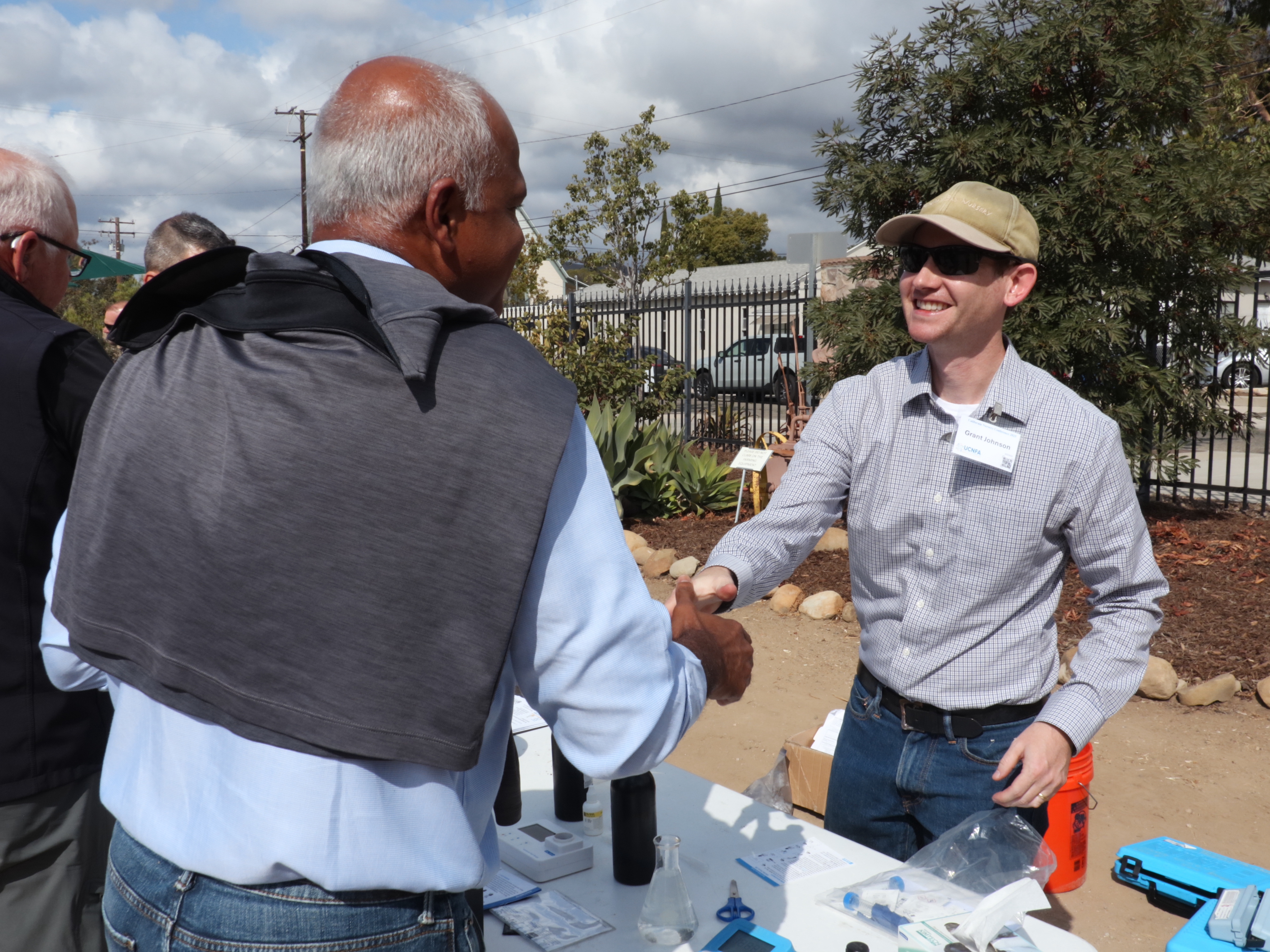 A photo of a man giving a demonstration shaking hands with a conference attendee.