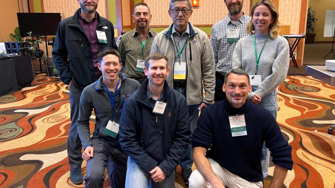 A photo of eight UCNFA members gathered in a conference room smiling.