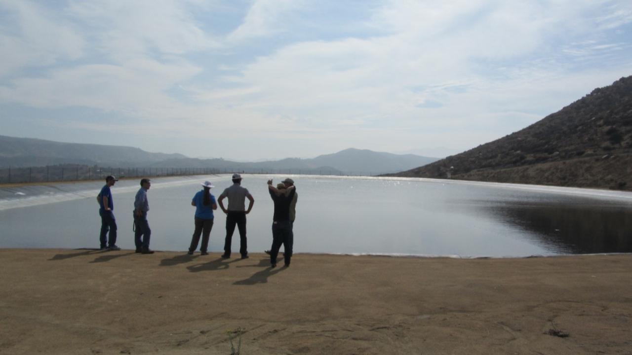 Five people looking out over a very large recycled water pond